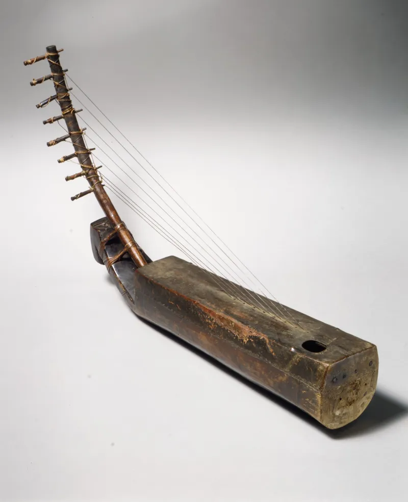 A small stringed instrument with a slender neck rising from a compact body closed with stretched skin, fibre bindings visible at the joins.